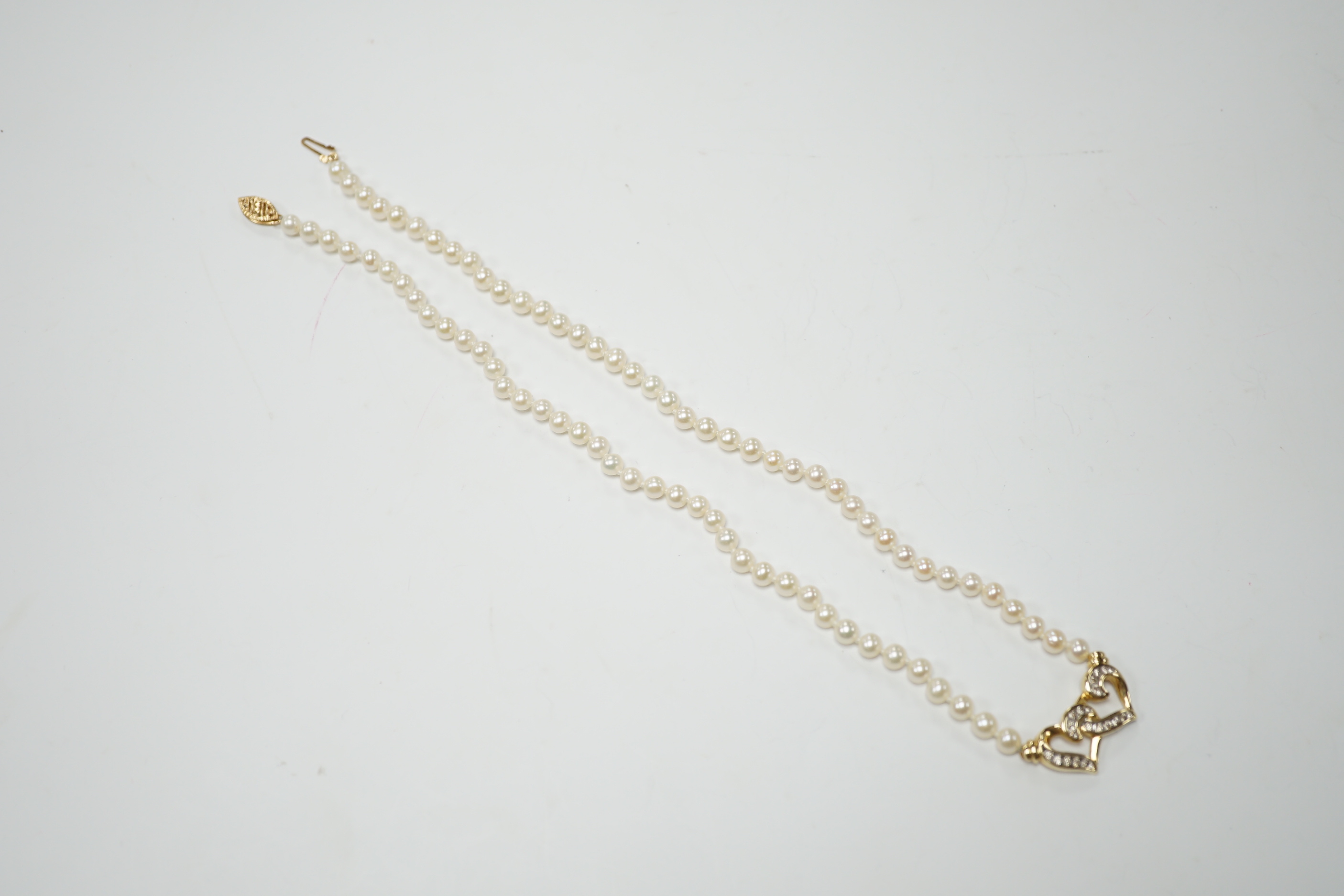 A modern single strand cultured pearl necklace, with central diamond chip set 14k yellow metal twin hearts motif, 42cm, gross weight 15.2 grams.